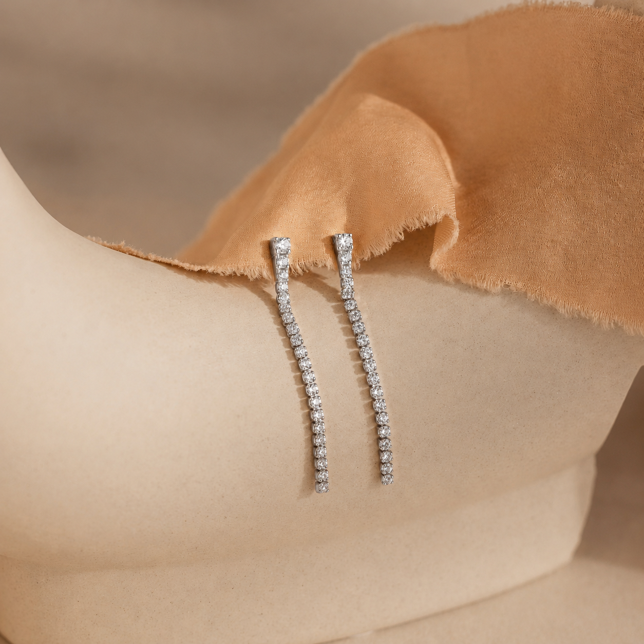 Pair of diamond earrings on a beige fabric background